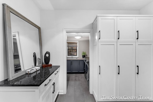 interior space featuring dark hardwood / wood-style flooring, white cabinetry, washing machine and dryer, and dark stone countertops