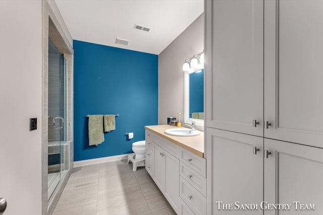 bathroom featuring tile patterned floors, a shower with door, vanity, and toilet