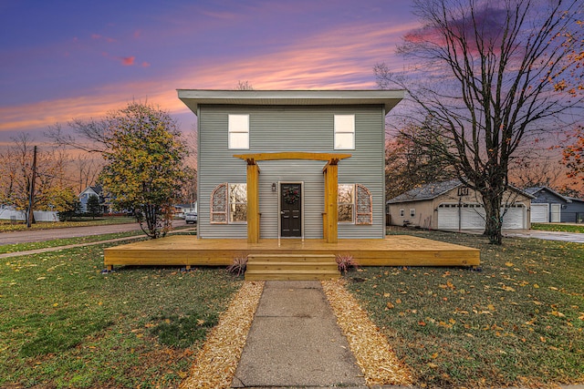 view of front of house with a garage, an outbuilding, and a lawn