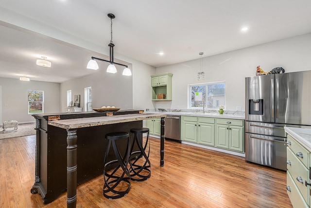 kitchen featuring green cabinets, stainless steel appliances, a kitchen breakfast bar, a kitchen island, and light wood-type flooring