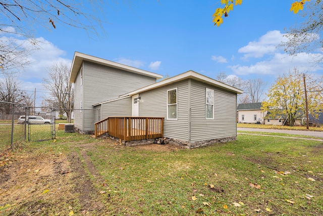 rear view of house featuring a wooden deck, a yard, and cooling unit