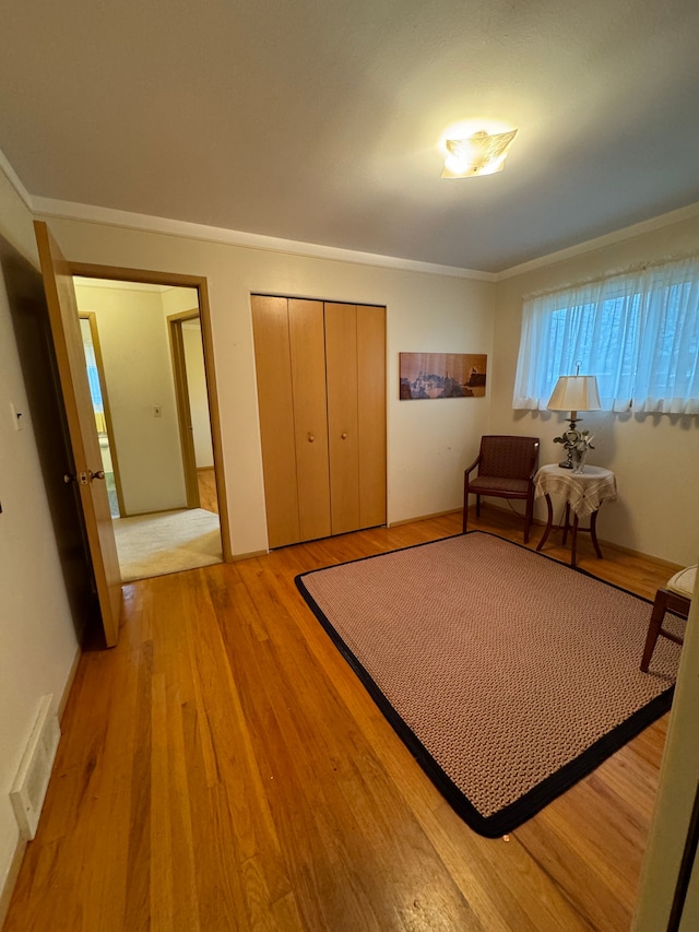 sitting room with ornamental molding and light wood-type flooring