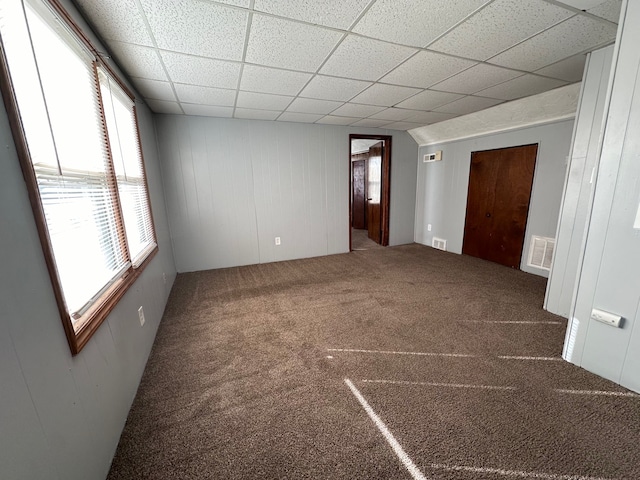 carpeted empty room with a drop ceiling