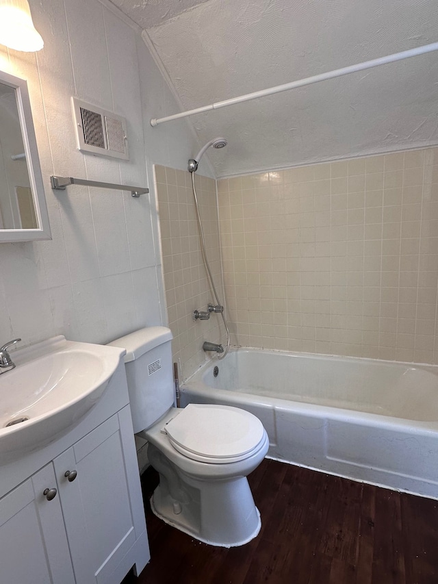 full bathroom featuring hardwood / wood-style floors, vanity, tiled shower / bath, toilet, and a textured ceiling