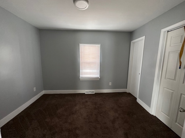 spare room featuring dark colored carpet