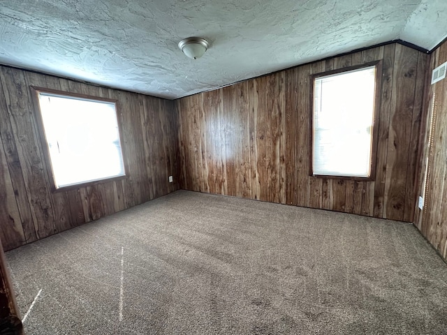 carpeted empty room featuring lofted ceiling and wood walls