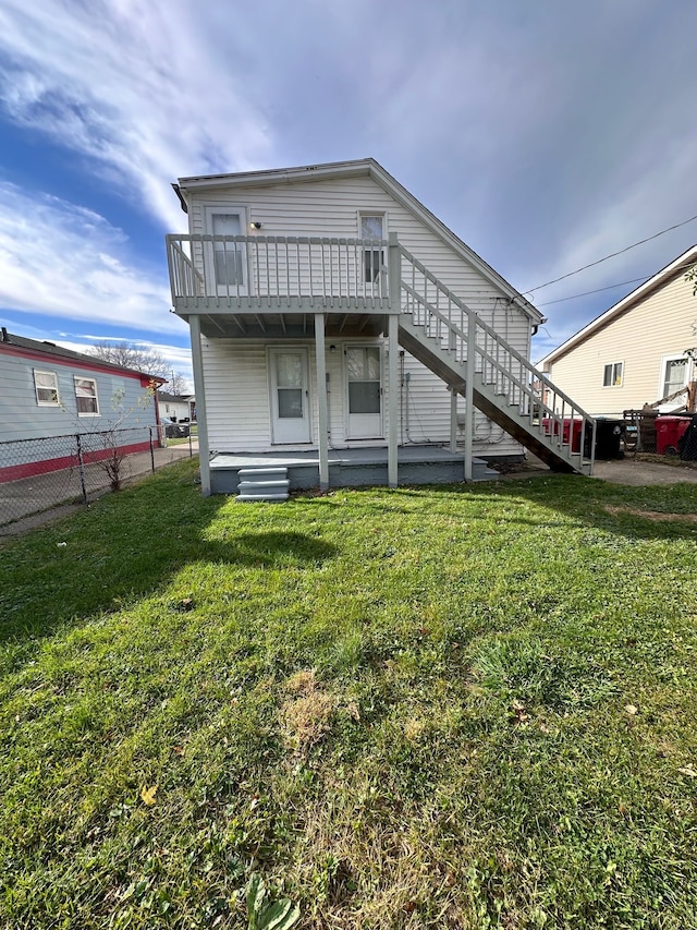 rear view of house featuring a balcony and a yard