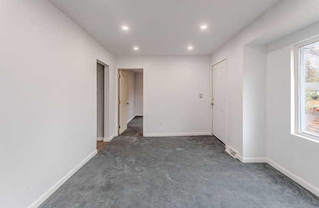 unfurnished room featuring dark colored carpet