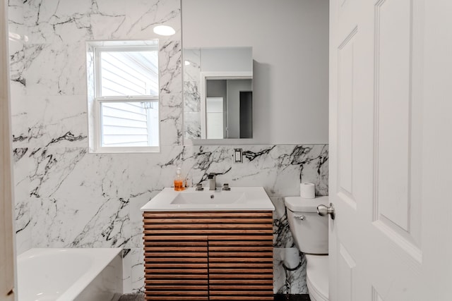 bathroom with vanity, a bathtub, toilet, and tile walls