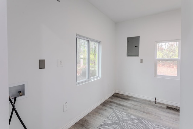 laundry room featuring electric panel, hookup for a washing machine, a healthy amount of sunlight, and light wood-type flooring