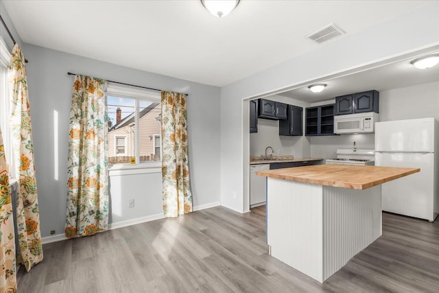 kitchen with hardwood / wood-style floors, wooden counters, white appliances, and sink