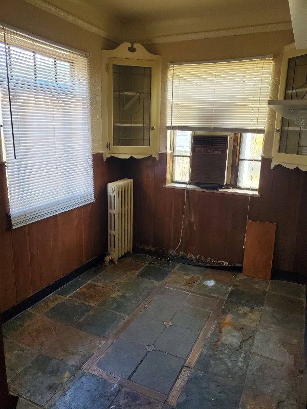 17366 Monica St, Detroit, MI 48221 - unfurnished room with radiator heating unit, stone tile floors, wooden walls, and crown molding