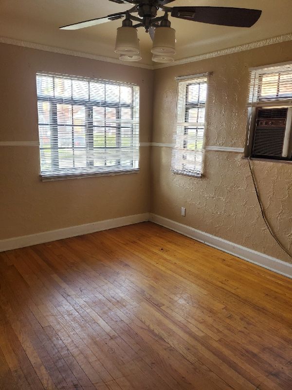 17366 Monica St, Detroit, MI 48221 - empty room featuring a ceiling fan, hardwood / wood-style flooring, baseboards, cooling unit, and a textured wall