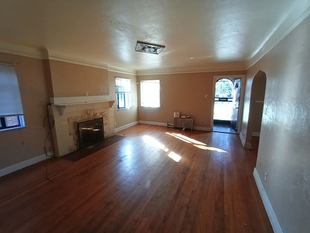 17366 Monica St, Detroit, MI 48221 - unfurnished living room with baseboards, radiator, arched walkways, wood finished floors, and a tiled fireplace