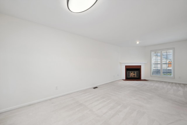 unfurnished living room with visible vents, a fireplace with flush hearth, light colored carpet, baseboards, and recessed lighting
