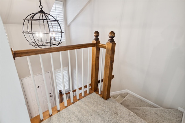 stairway with baseboards, carpet flooring, and a notable chandelier