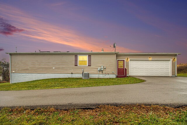 view of front of house featuring a lawn, central AC unit, and a garage