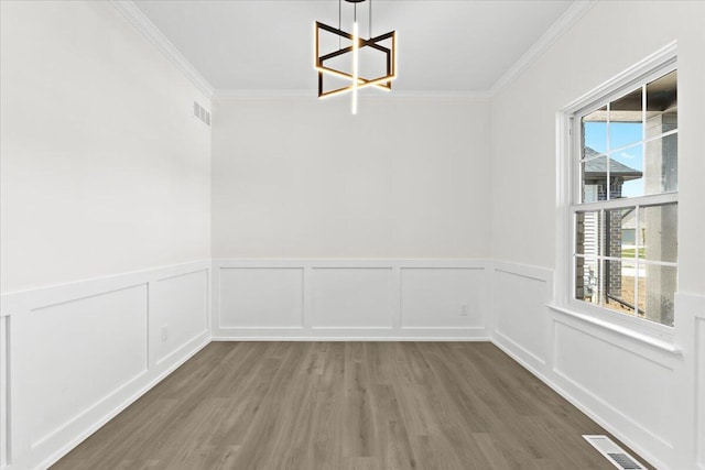 36135 Parkdale St Unit 5, Livonia, MI 48150 - unfurnished dining area featuring a chandelier, crown molding, wood finished floors, a wainscoted wall, and a decorative wall