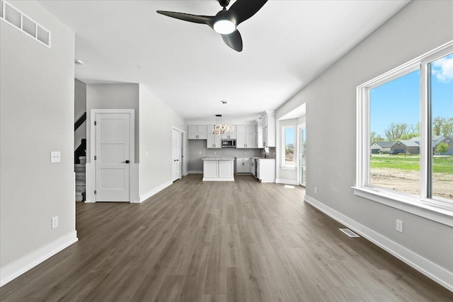 36135 Parkdale St Unit 5, Livonia, MI 48150 - unfurnished living room featuring dark wood-type flooring, a chandelier, a ceiling fan, baseboards, and stairs