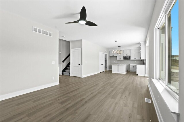 36135 Parkdale St Unit 5, Livonia, MI 48150 - unfurnished living room featuring a ceiling fan, a chandelier, wood finished floors, stairs, and baseboards