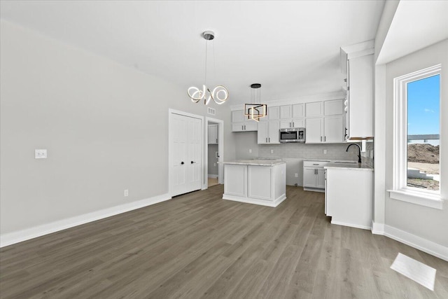 36135 Parkdale St Unit 5, Livonia, MI 48150 - kitchen with stainless steel microwave, a sink, wood finished floors, white cabinetry, and decorative backsplash
