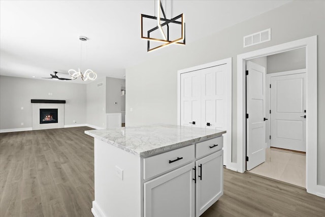 36135 Parkdale St Unit 5, Livonia, MI 48150 - kitchen with a chandelier, light wood finished floors, a kitchen island, light stone countertops, and pendant lighting