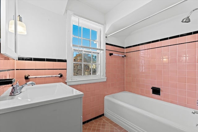 bathroom featuring tiled shower / bath combo, tile patterned floors, tile walls, and sink