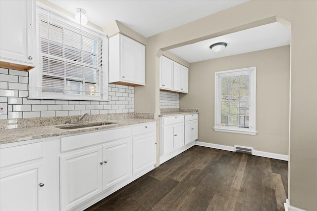 kitchen featuring white cabinets, sink, tasteful backsplash, dark hardwood / wood-style flooring, and light stone counters