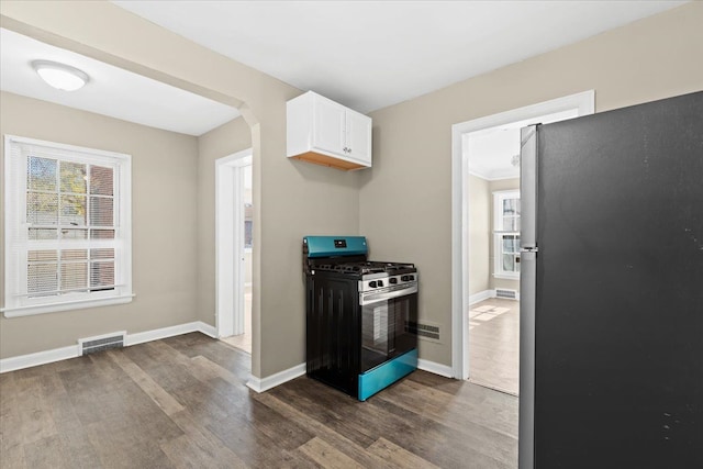 kitchen with stainless steel refrigerator, white cabinetry, dark hardwood / wood-style flooring, and range with gas stovetop