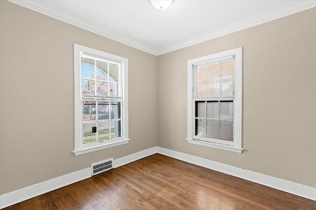 spare room featuring crown molding, plenty of natural light, and hardwood / wood-style floors