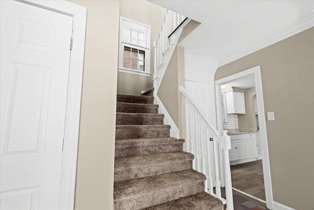 stairs with hardwood / wood-style flooring and crown molding