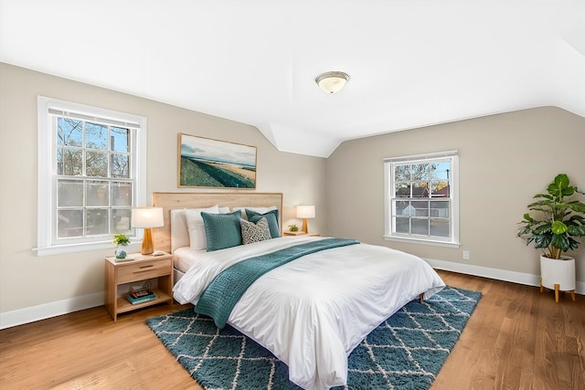 bedroom featuring hardwood / wood-style floors, lofted ceiling, and multiple windows