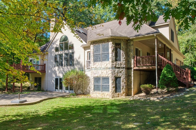 rear view of property featuring a lawn, a patio area, and a deck