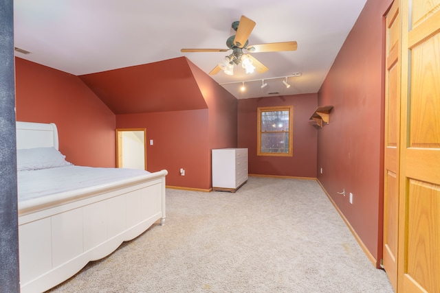 unfurnished bedroom with rail lighting, ceiling fan, lofted ceiling, and light carpet