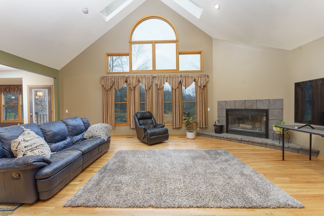 living room featuring a skylight, hardwood / wood-style floors, and high vaulted ceiling