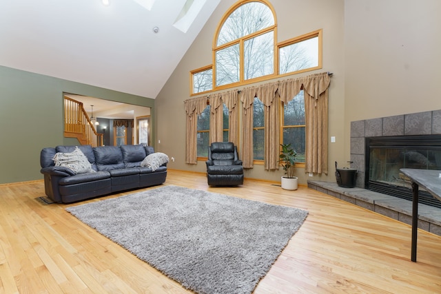 living room featuring hardwood / wood-style floors, a skylight, and high vaulted ceiling