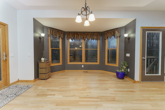 unfurnished dining area with light hardwood / wood-style floors and an inviting chandelier