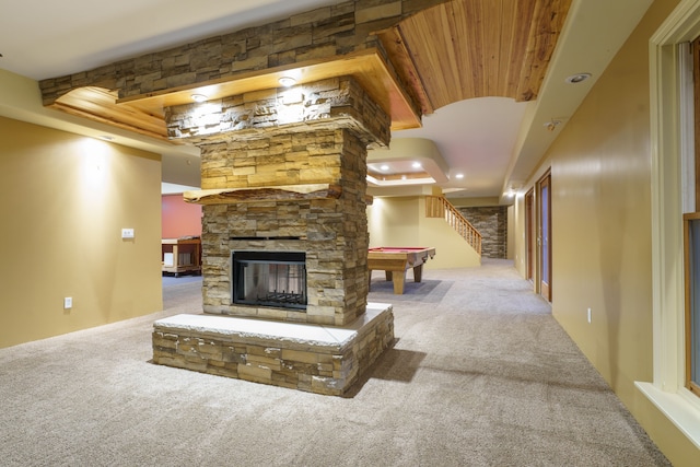 unfurnished living room featuring light carpet, a tray ceiling, a fireplace, and billiards