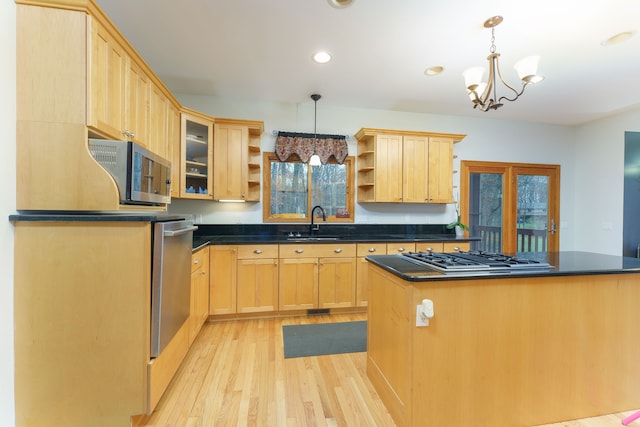 kitchen featuring light brown cabinets, a kitchen island, hanging light fixtures, and light wood-type flooring