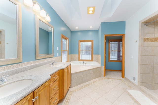 bathroom featuring plus walk in shower, vanity, a skylight, and tile patterned floors