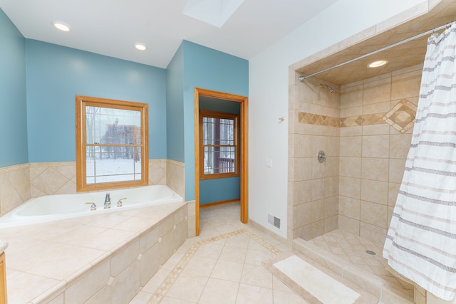 bathroom with shower with separate bathtub, a skylight, and tile patterned floors