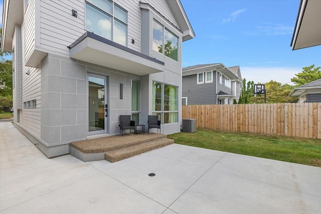 rear view of property featuring a lawn, cooling unit, and a patio area