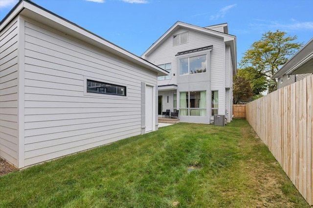 rear view of property with central AC and a lawn