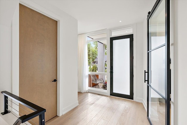 entryway with a barn door and light hardwood / wood-style flooring