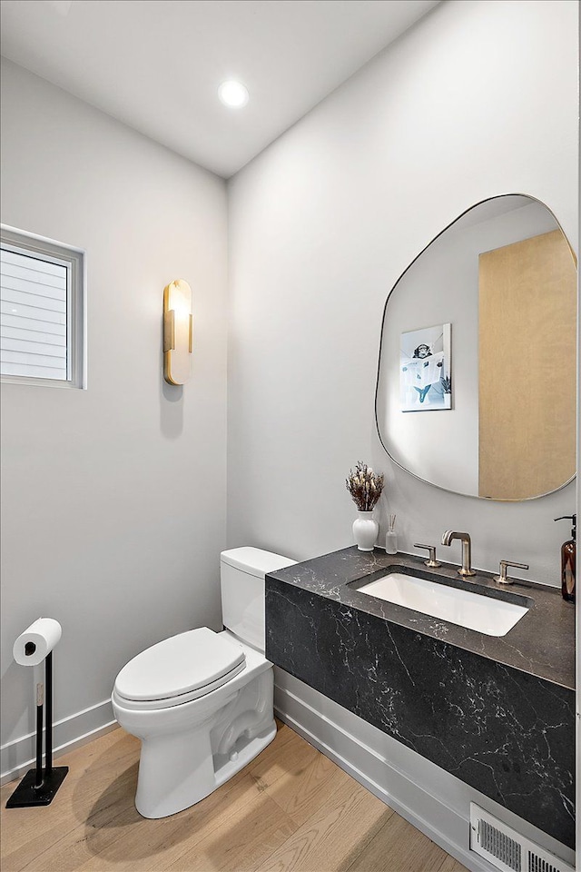 bathroom with toilet, wood-type flooring, and sink