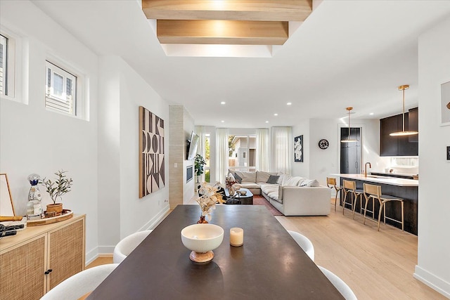 dining area with sink, beamed ceiling, and light hardwood / wood-style floors