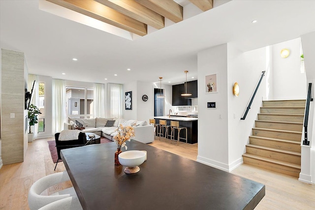 dining area with light hardwood / wood-style flooring, beamed ceiling, and sink