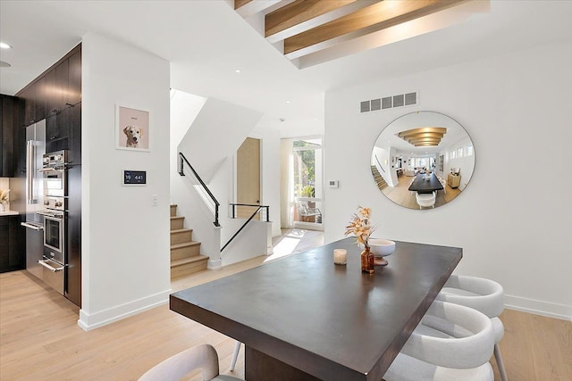 dining space with beam ceiling and light hardwood / wood-style floors