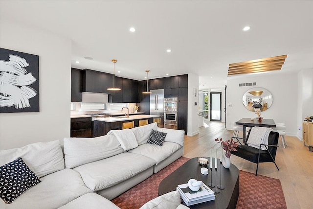 living room featuring sink and light hardwood / wood-style floors