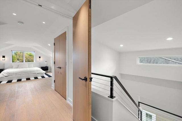 corridor with light hardwood / wood-style flooring and lofted ceiling